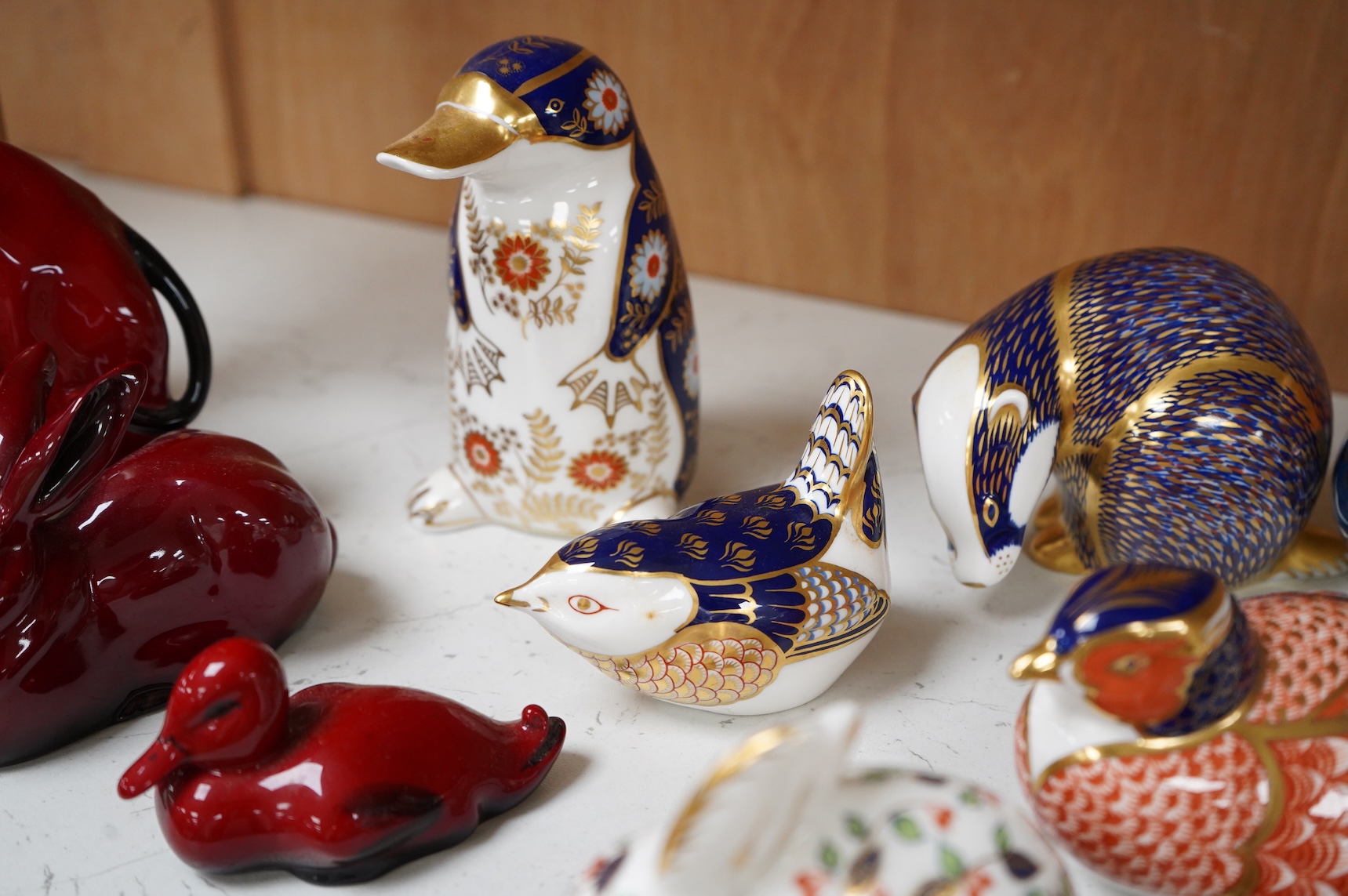 A collection of Royal Crown Derby Imari pattern paperweights, to include penguin and badger, together with three Doulton flambé animals, largest 19cm wide
